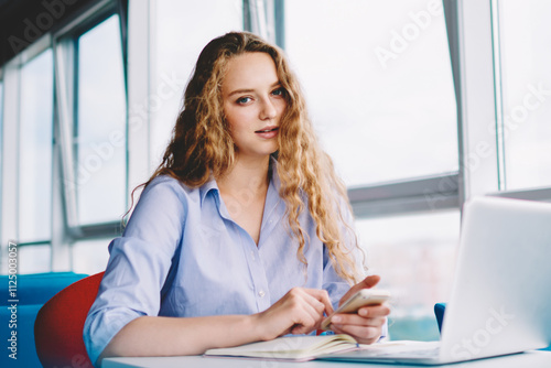 Portrait of tired female freelancer holding smartphone gadget in hand and looking at camera while sitting at desk with laptop computer, young caucasian hipster girl using technology and good internet Free Download Portrait of tired female freelancer holding smartphone gadget in hand and looking at camera while sitting at desk with laptop computer, young caucasian hipster girl using technology and good internet - GFXLoad