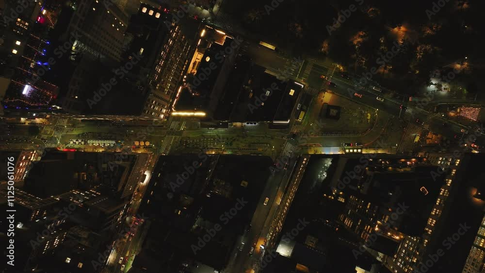 Aerial view of a busy intersection in Manhattan, New York City at night. Cars are driving through intersection and city lights shine brightly Aerial view of a busy intersection in Manhattan, New York City at night. Cars are driving through intersection and city lights shine brightly