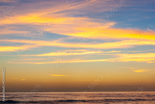 Dramatic Sunset Over Calm Ocean With Vibrant Clouds In The Sky