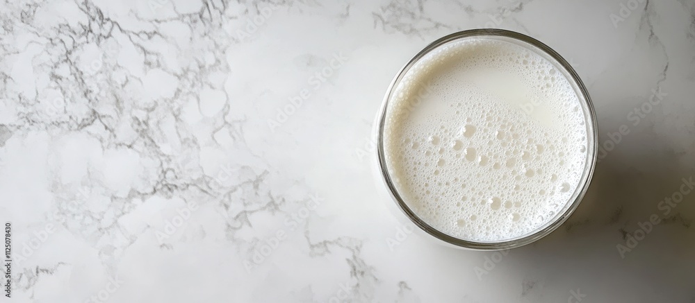 A glass of fresh cold milk with condensation on the glass, placed on a white marble counter A glass of fresh cold milk with condensation on the glass, placed on a white marble counter