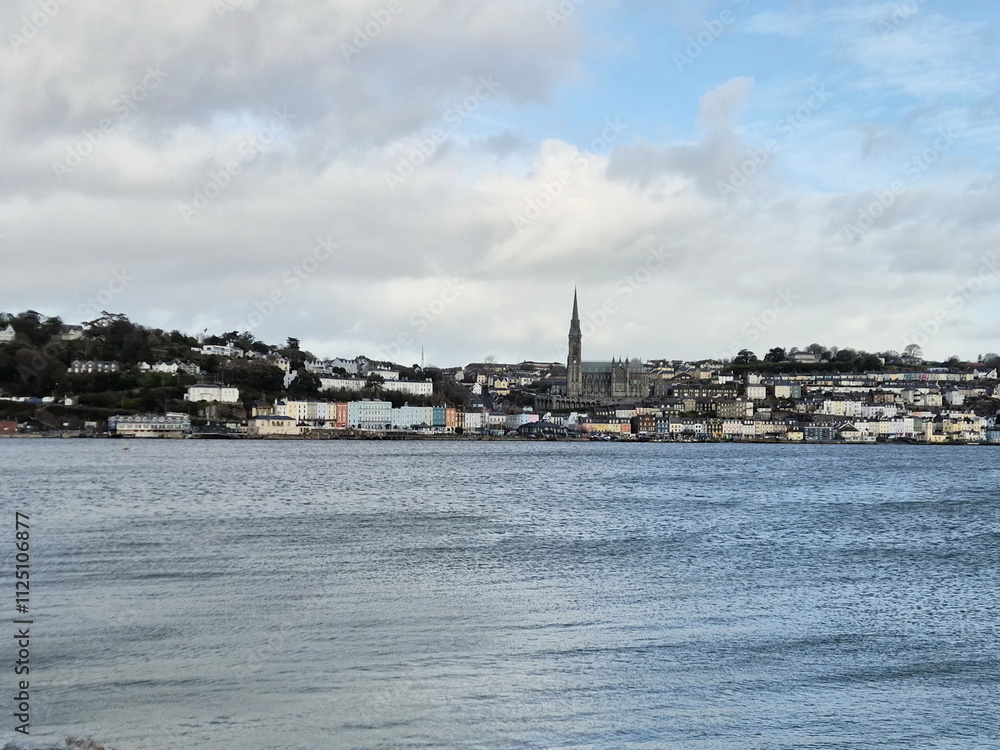 Fototapeta premium Cobh city in Cork county of Ireland, urban cityscape as it is seen from the island, with stormy cloudy sky and ocean