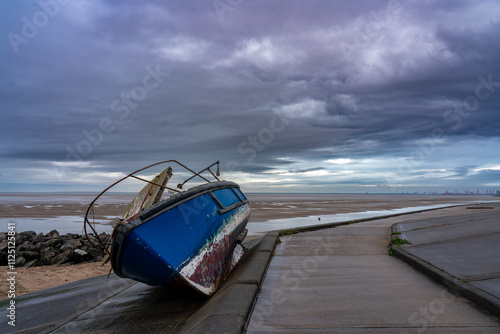 Derelict fishing boat swept onto sloping concrete breakwater during storm photo