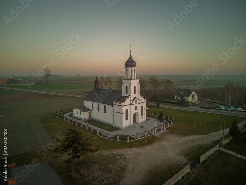 Small, white Catholic church in the light of the setting sun.