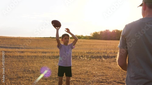 Happy family playing ball: boy and father play american football. boy rugby ball passes dad in an outdoor activity. Experience the joy of family fun and teamwork