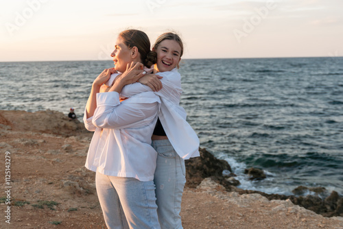 Mother Daughter Beach Sunset - Happy mother and daughter embracing at sunset on a beach.