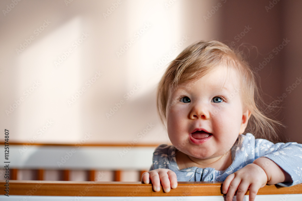Portrait of a cute Caucasian baby girl 7 months old standing in a crib and looking at the camera. Copy space Portrait of a cute Caucasian baby girl 7 months old standing in a crib and looking at the camera. Copy space