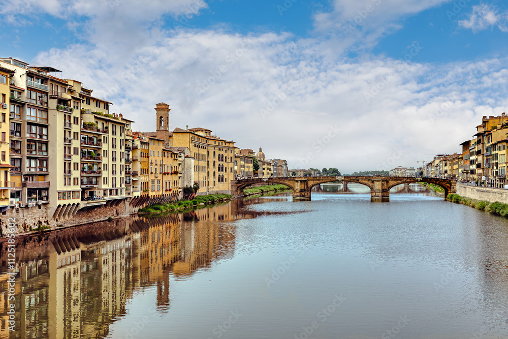 Fototapeta premium View of the of Arno River with Santa Trinita Bridge and Florence's stunning architecture the banks and a clear blue sky above
