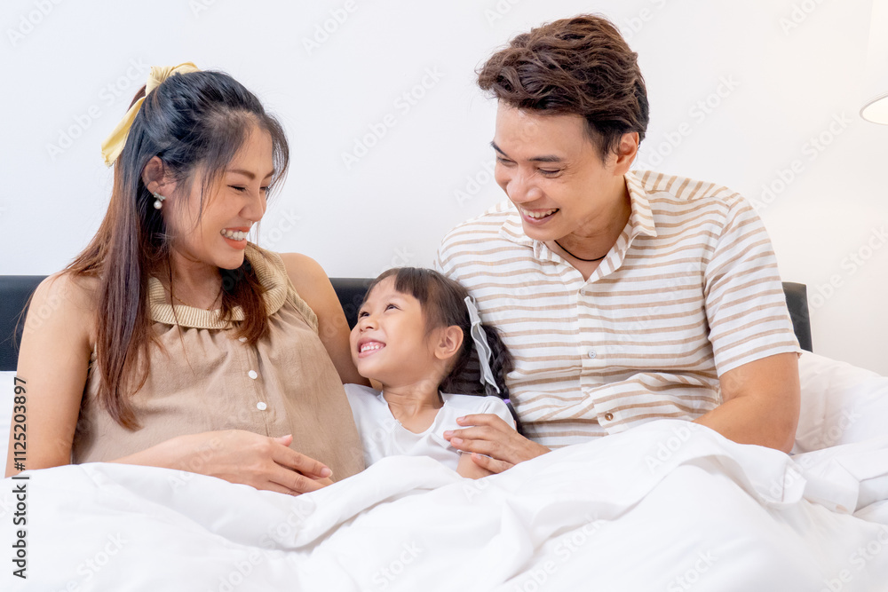 Close up Asian family with pregnant mother, father and little daughter enjoy to stay on bed together in bedroom of their house. Close up Asian family with pregnant mother, father and little daughter enjoy to stay on bed together in bedroom of their house.