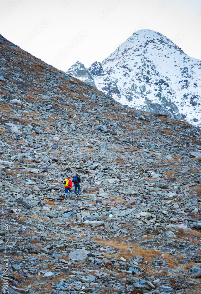 a pair of unrecognizable climbers walk up a rocky mountain a pair of unrecognizable climbers walk up a rocky mountain