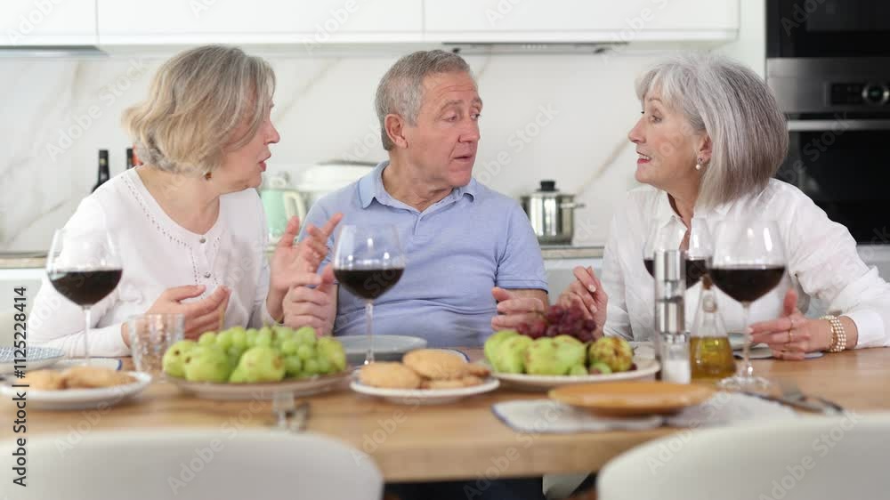 Joyful retirees gathered around a celebratory table, engaging in lively conversations and indulging in the pleasures of red wine Joyful retirees gathered around a celebratory table, engaging in lively conversations and indulging in the pleasures of red wine