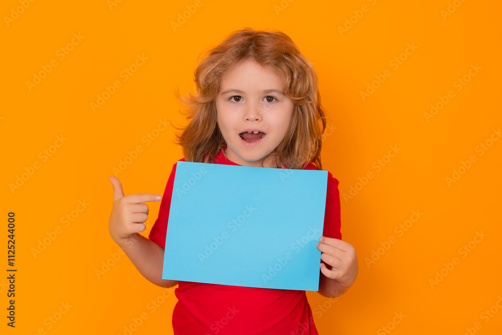 Excited kid boy showing blank banner on yellow background . Advertising billboard, placard. Child hold empty color blank sheet of paper, copy spase. Surprised face, amazed emotions of child. Excited kid boy showing blank banner on yellow background . Advertising billboard, placard. Child hold empty color blank sheet of paper, copy spase. Surprised face, amazed emotions of child.