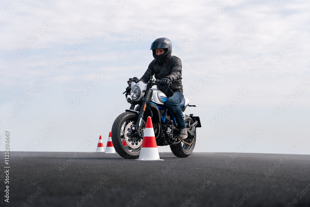 Motorcycle rider riding between traffic cones. Motorcycle rider riding between traffic cones.