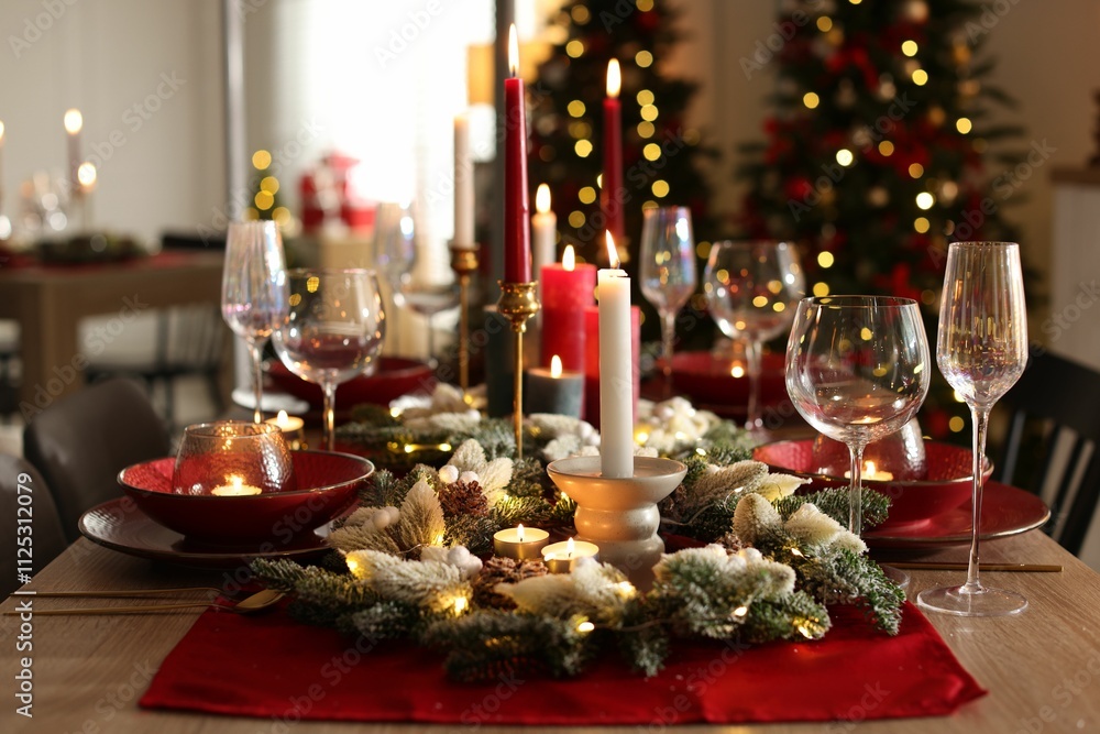 Christmas table setting with stylish dishware, glasses and burning candles in festive decorated room Christmas table setting with stylish dishware, glasses and burning candles in festive decorated room