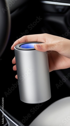 A sleek, silver device is held in a hand, likely a modern car accessory, resting in a vehicle's interior, possibly for aroma diffusion or air purification. photo