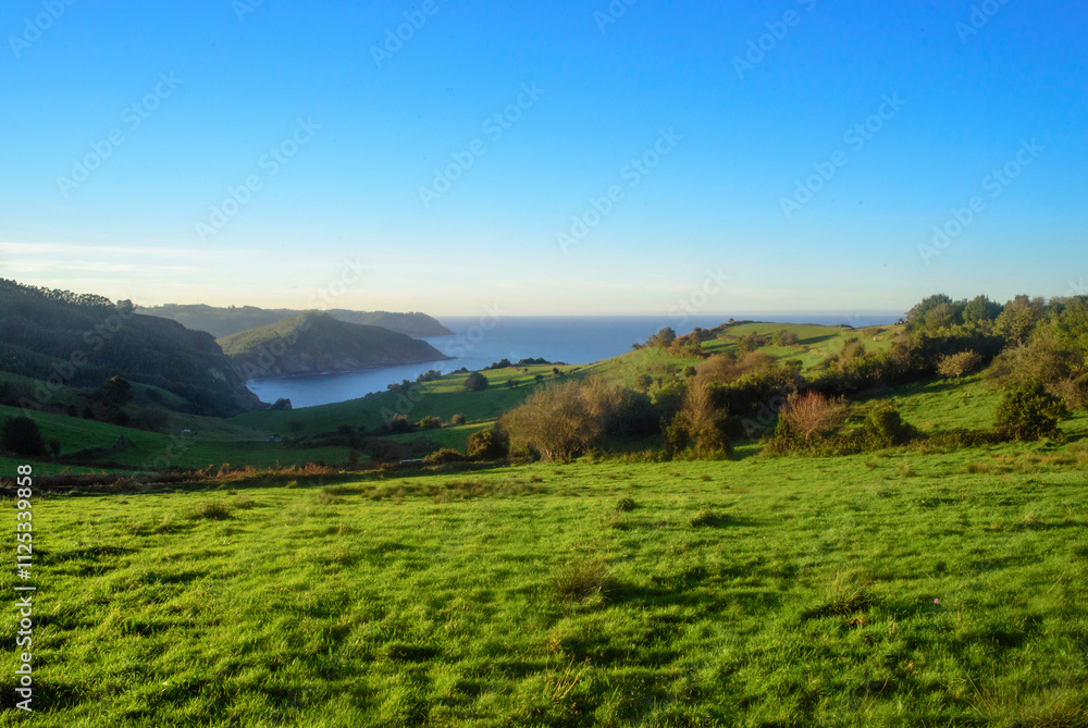 Bahía y horizonte marino tras praderas verdes en litoral de Asturias Bahía y horizonte marino tras praderas verdes en litoral de Asturias