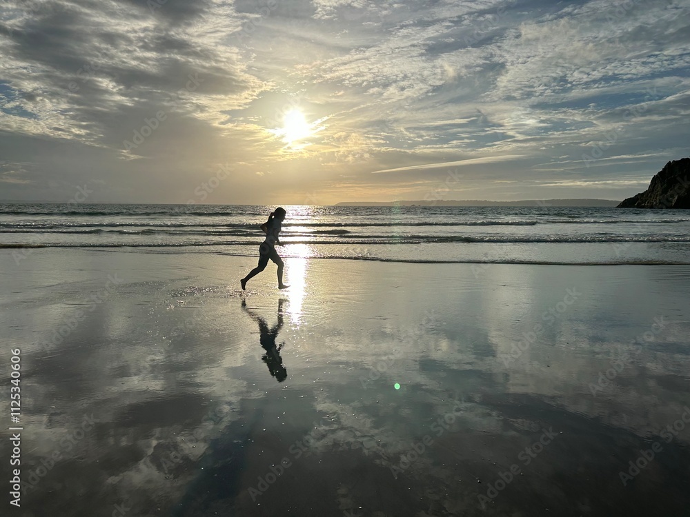 Jeune fille courant sur la plage lors d'un coucher de soleil Jeune fille courant sur la plage lors d'un coucher de soleil