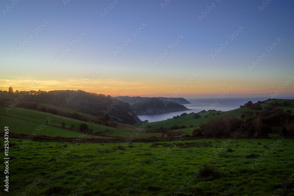 Fototapeta premium Atardecer en bahía tras prados verde en litoral de Asturias
