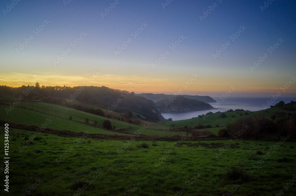 Atardecer en bahía tras prados verde en litoral de Asturias Atardecer en bahía tras prados verde en litoral de Asturias