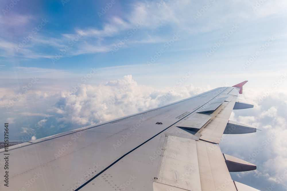 View from the airplane window at a beautiful cloudy sky and the airplane wing View from the airplane window at a beautiful cloudy sky and the airplane wing