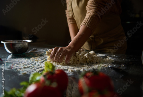 Photos Person kneading dough on a floured surface in a warm kitchen setting