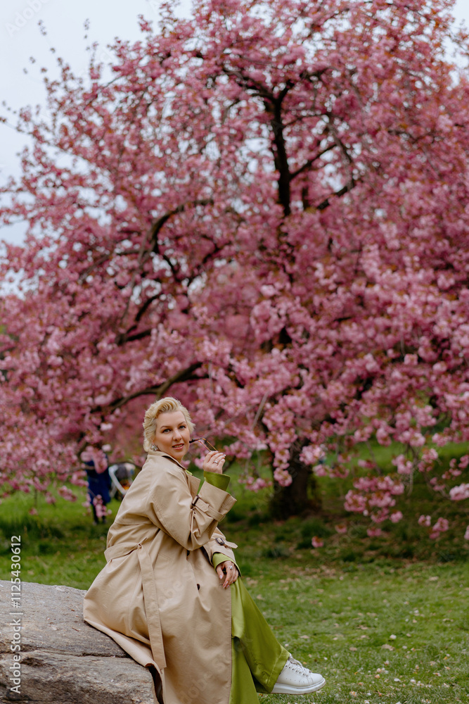 Woman Relaxing on Stone Bench under Beautiful Blooming Cherry Blossom Tree Woman Relaxing on Stone Bench under Beautiful Blooming Cherry Blossom Tree