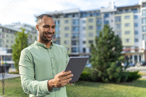 Businessman with tablet standing near buildings checking built project