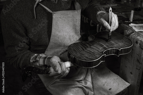Italian violin maker applying varnish on a violin in his workshop