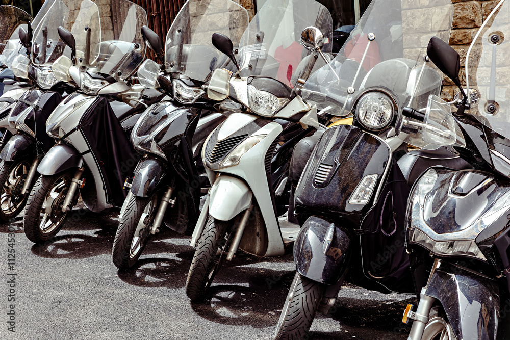 Several motorcycles are marked neatly on a cobbled street in the heart of Florence, surrounded by history medieval buildings and vibrant city life.