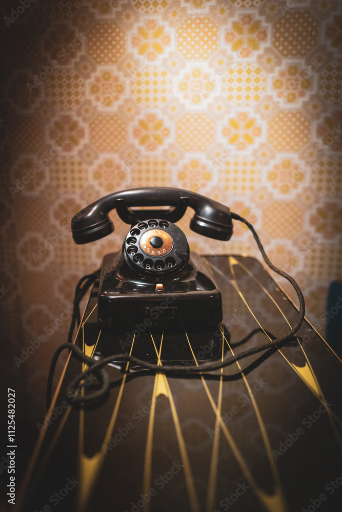 There is an old black dial telephone on the table