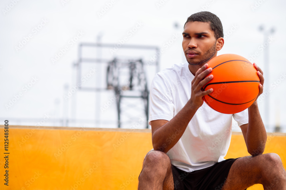 Young man with a ball in hands sitting with a serious look Young man with a ball in hands sitting with a serious look