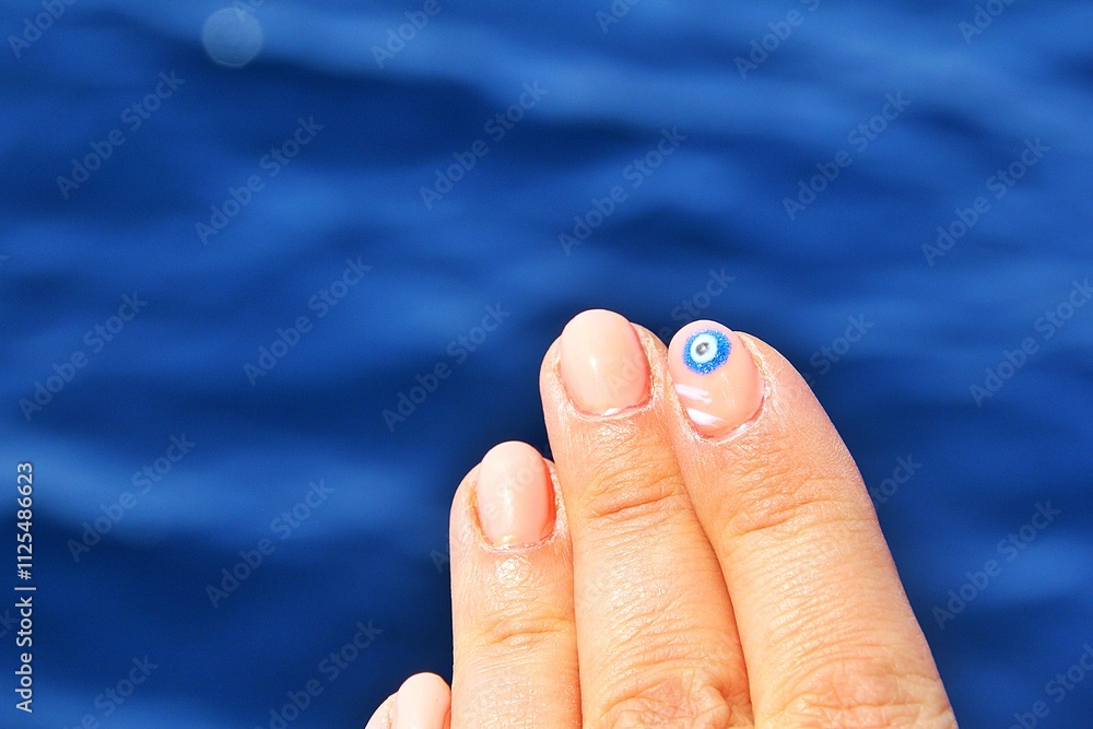 Naklejka premium hand, fingers above water, fingers and painted nail with the eye of the prophet, eye of the prophet painted on nail
