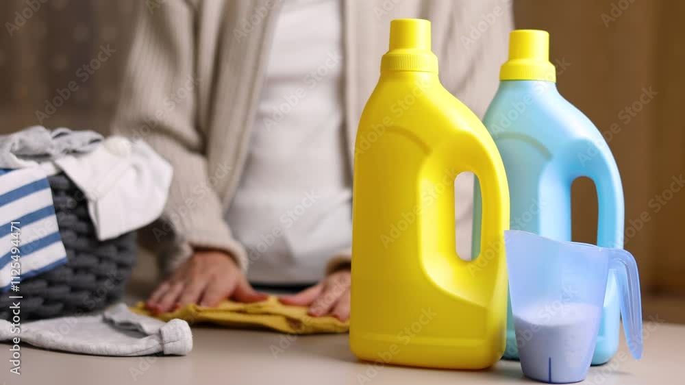 A woman folds baby things after washing. Detergents for washing children's clothes A woman folds baby things after washing. Detergents for washing children's clothes