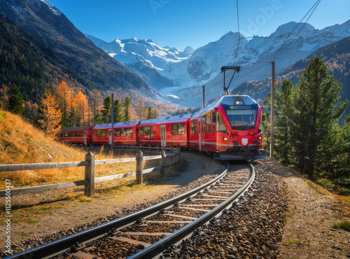 Red modern electric train traveling along a railway, winding through a stunning high mountains with snow-capped peaks and vibrant autumn trees in switzerland. Bernina Express in fall. Railway tourism