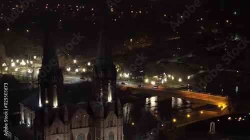 Aerial view of a historic church and brightly lit bridge in Anykščiai, Lithuania, under the serene night sky. photo