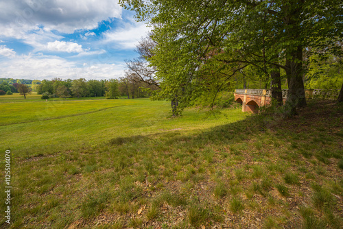 Idyllic Countryside Meadow with a Historic Brick Bridge and Trees