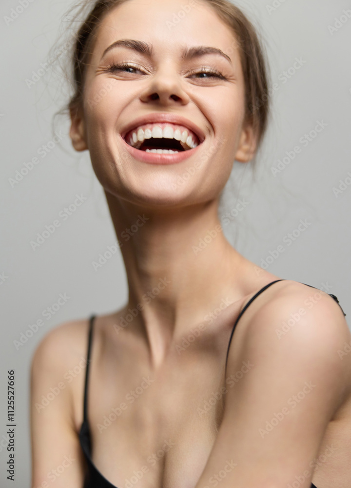 Joyful young woman with long hair, wearing a black top, smiling brightly against a neutral background. Happiness and confidence concept captured in portrait. Joyful young woman with long hair, wearing a black top, smiling brightly against a neutral background. Happiness and confidence concept captured in portrait.