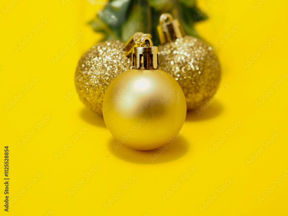 Golden decoration balls and green tree on yellow color background. Festive season concept. Copy space. Selective focus. Golden decoration balls and green tree on yellow color background. Festive season concept. Copy space. Selective focus.