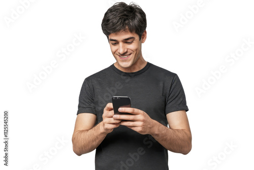 Young man standing, looking at screen of phone with smile, browsing web pages or chatting with friend
 photo