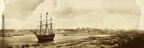 An antique ship anchors at a quiet coastal location, capturing a moment of maritime history and beauty. photo