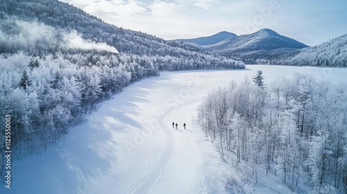 Hikers on snowy trail by frozen lake and winter mountains.