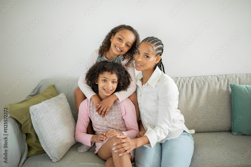 A loving mother sits on a sofa with her two daughters, showcasing their strong bond and affection for each other in their comfortable home environment. A loving mother sits on a sofa with her two daughters, showcasing their strong bond and affection for each other in their comfortable home environment.