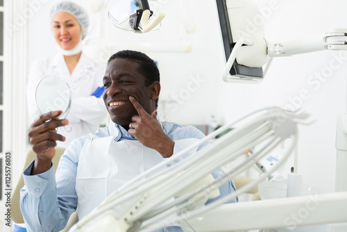 Portrait of happy african american patient satisfied after dental treatment in modern dentist office ..