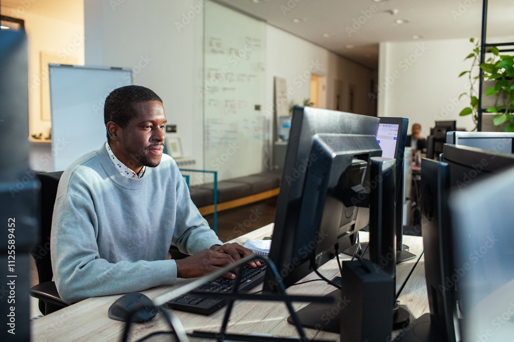 Focused man working on dual monitors in office Focused man working on dual monitors in office