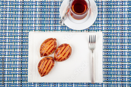 Traditional Turkish Dessert with Tea: Sekerpare. Sekerpare is served with tea on a white plate. photo