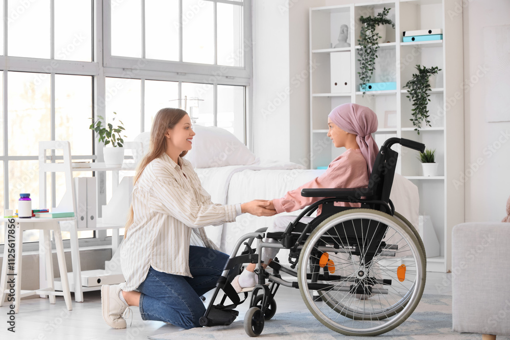 Little girl after chemotherapy in wheelchair with mother holding hands at hospital. Childhood cancer awareness concept Little girl after chemotherapy in wheelchair with mother holding hands at hospital. Childhood cancer awareness concept