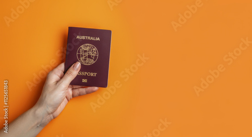 Hand holding red passport against orange background