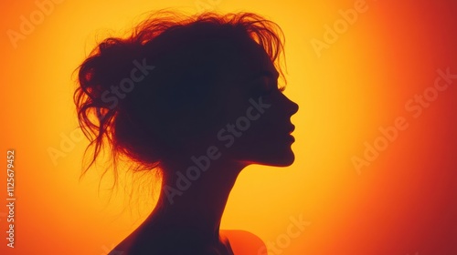 Silhouette of Woman with Curly Hair Against an Orange Backdrop at Sunset with Soft Lighting Effects