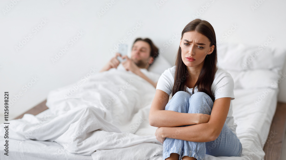 Unhappy Young Wife Suspecting Infidelity While Cheating Husband Texting On Smartphone Lying In Bed At Home. Selective Focus On Frustrated Woman Sitting In Bedroom. Jealousy Concept. Unhappy Young Wife Suspecting Infidelity While Cheating Husband Texting On Smartphone Lying In Bed At Home. Selective Focus On Frustrated Woman Sitting In Bedroom. Jealousy Concept.