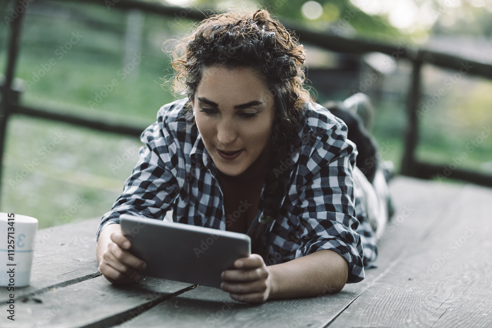 Fototapeta premium Young woman using digital tablet outdoors in a farm