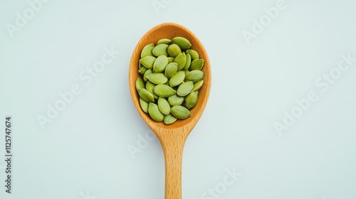 Close-up of a wooden spoon filled with vibrant green pumpkin seeds on a light-colored background, emphasizing healthy eating and nutritious food choices, culinary, wellness, organic. photo